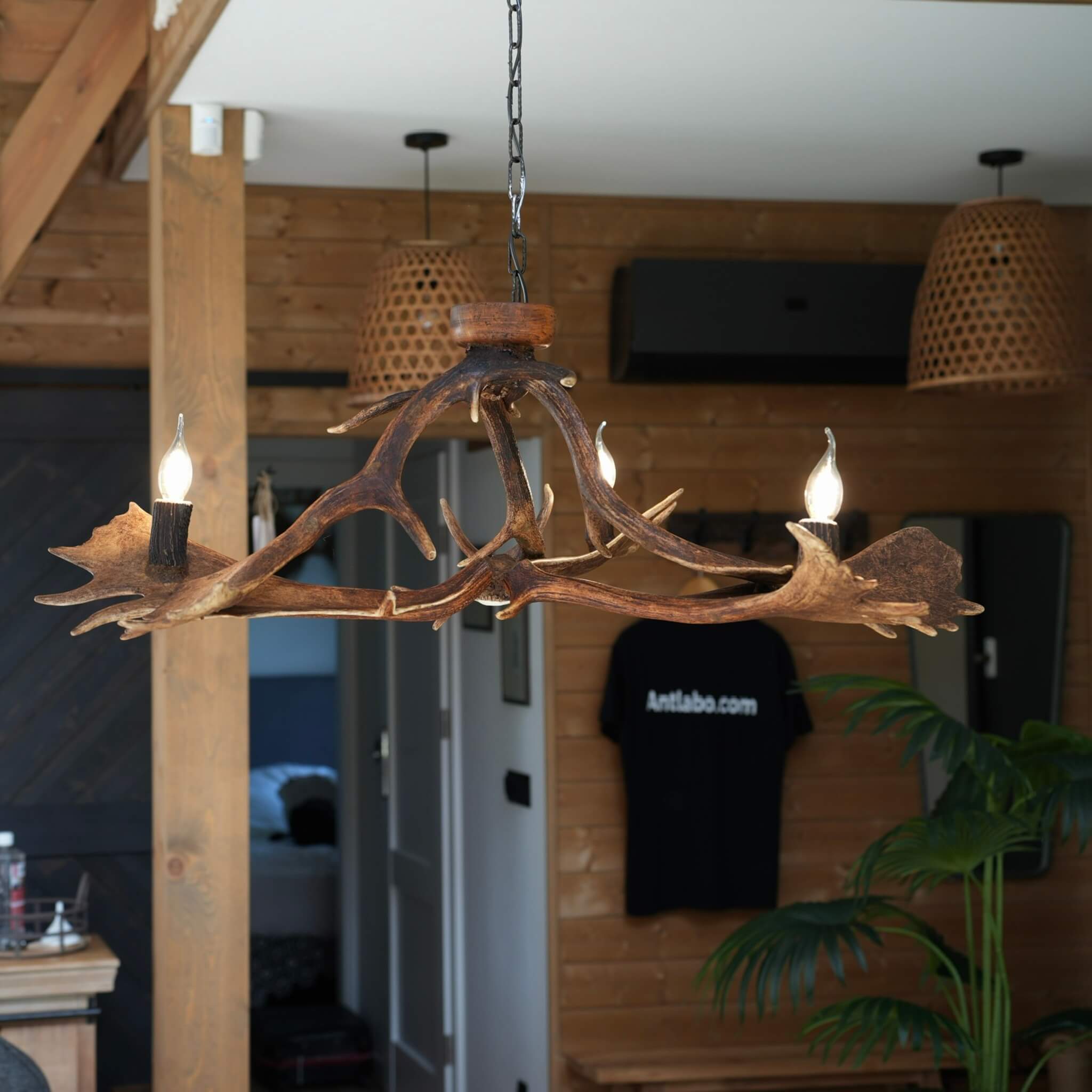 Low antler chandelier holding three warm lights, perfect for a countryside-inspired interior.