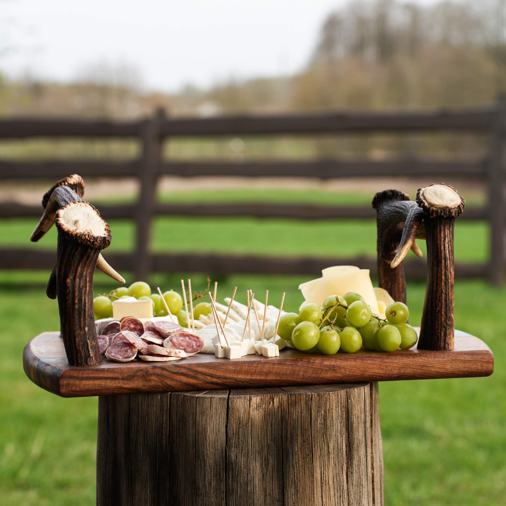Rustic olive wood tray with epoxy resin inlay and antler handles on a wooden table with natural lighting.