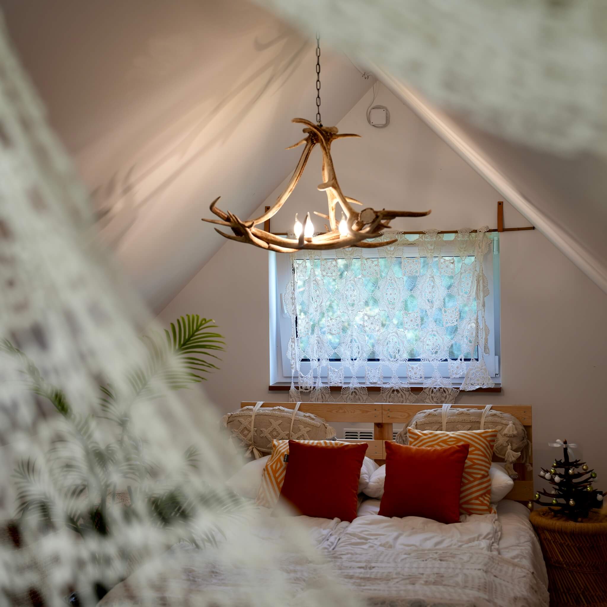 Bedroom with a bed, pillows, and a chandelier with antler design.
