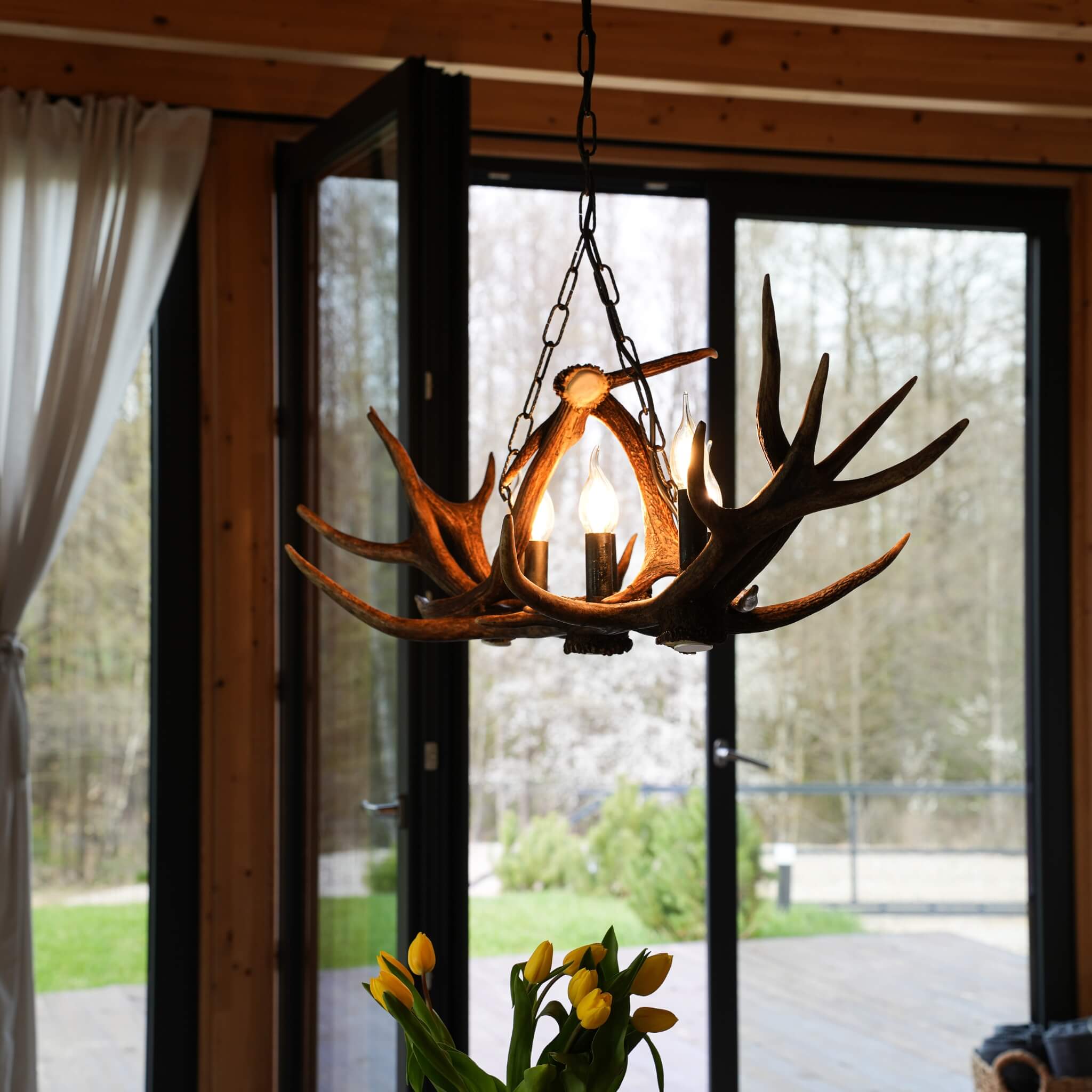 Real antler chandelier for 9 light hanging on chain over table.