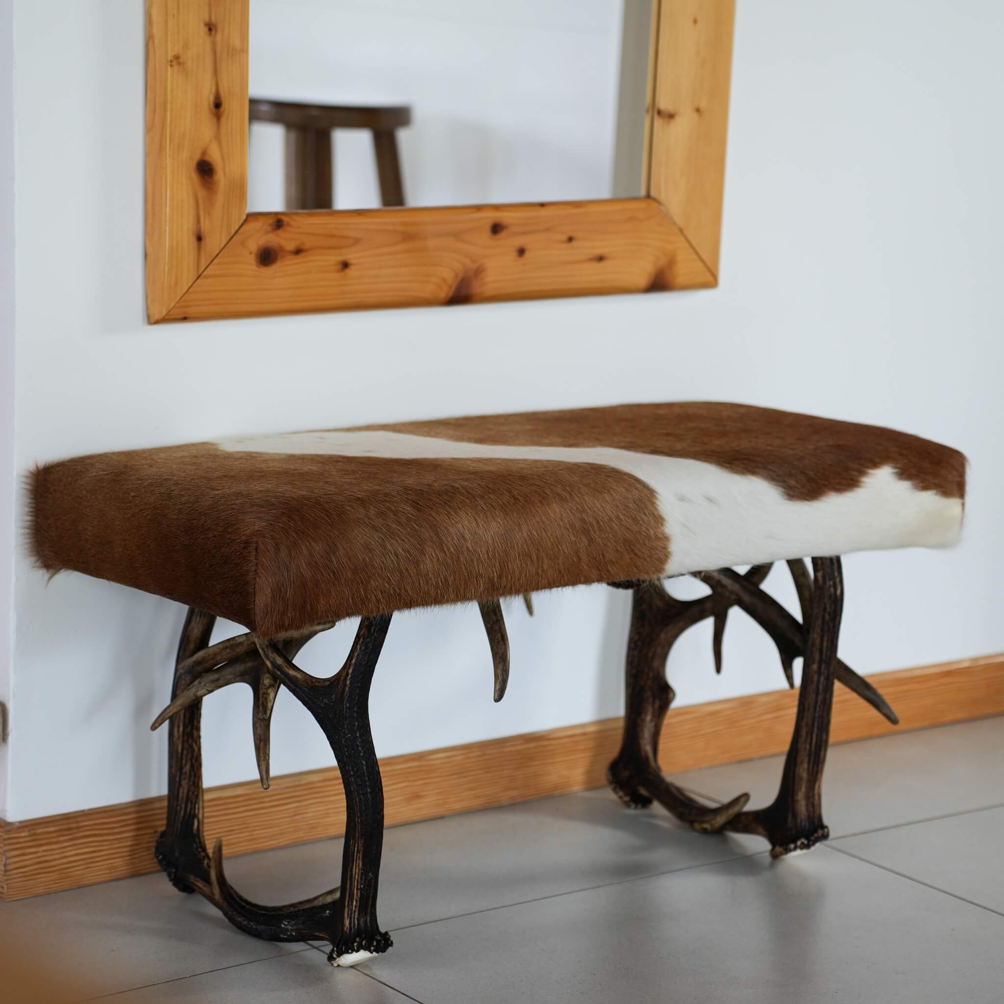 Antler cowhide bench standing by the mirror.