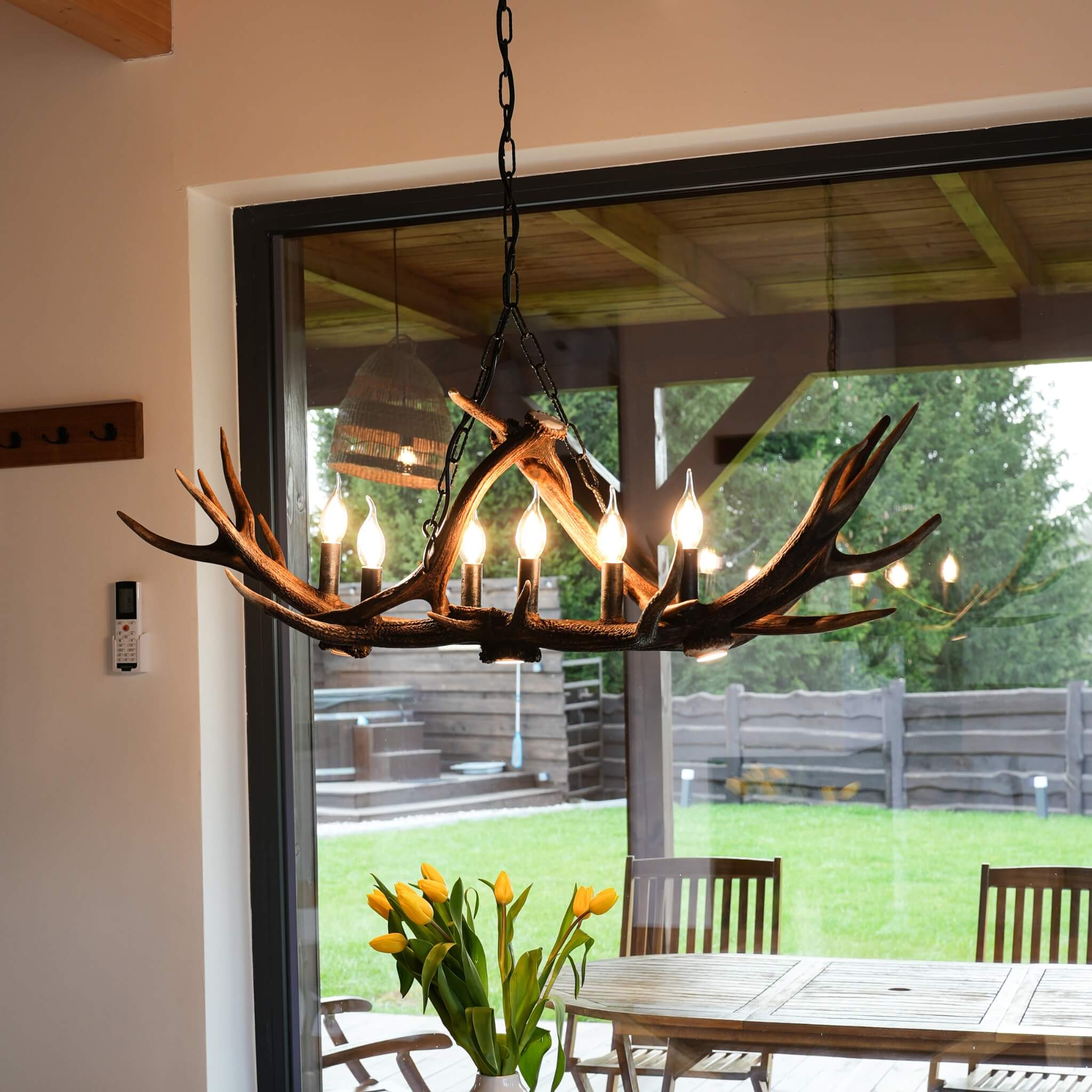 Antler chandelier over table in rustic cabin.