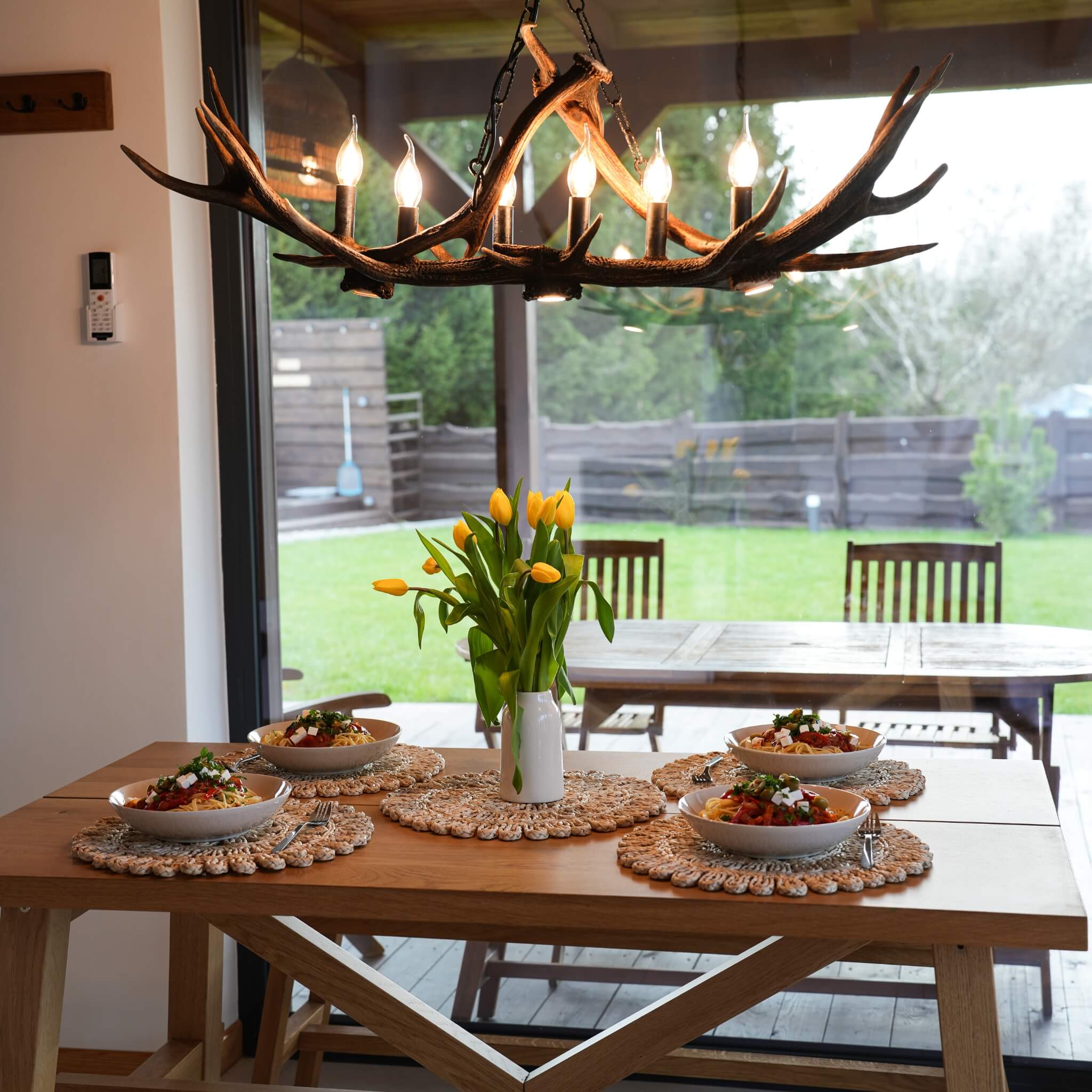 Real antler chandeleir with downlight hanging oved table in dining room.