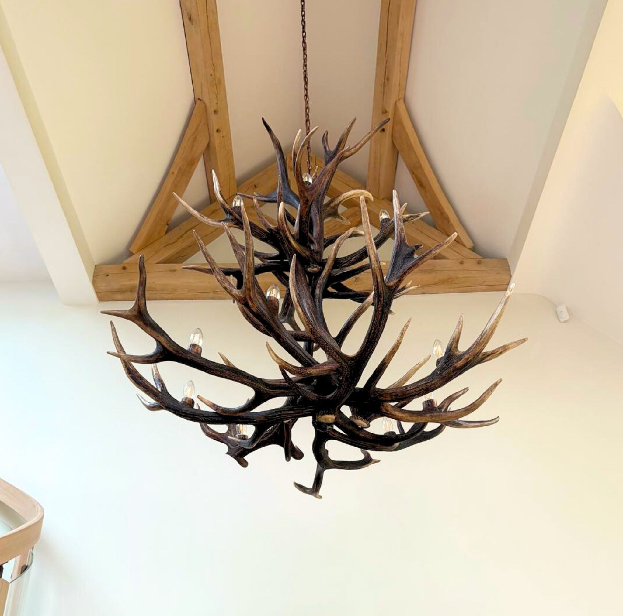 Antler chandelier hanging in a room with wooden beams.