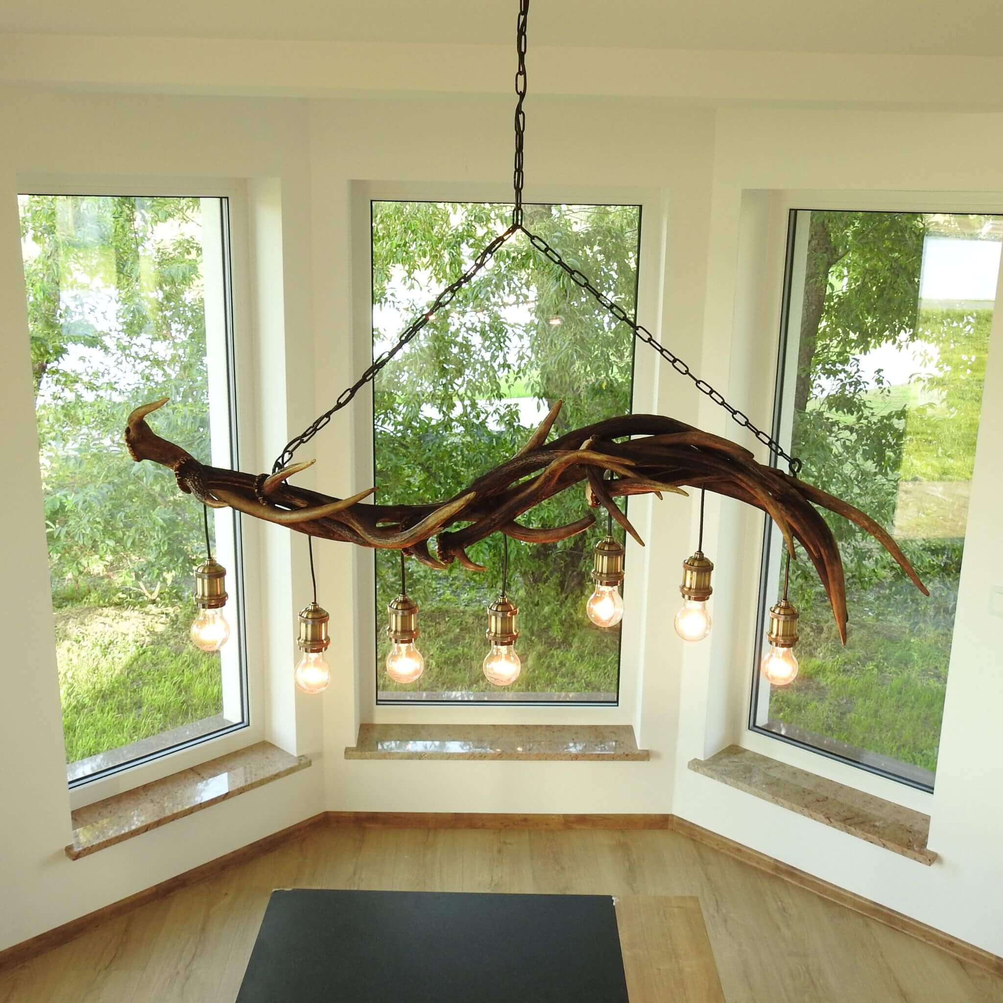 Linear antler chandelier hangs over table in living room.