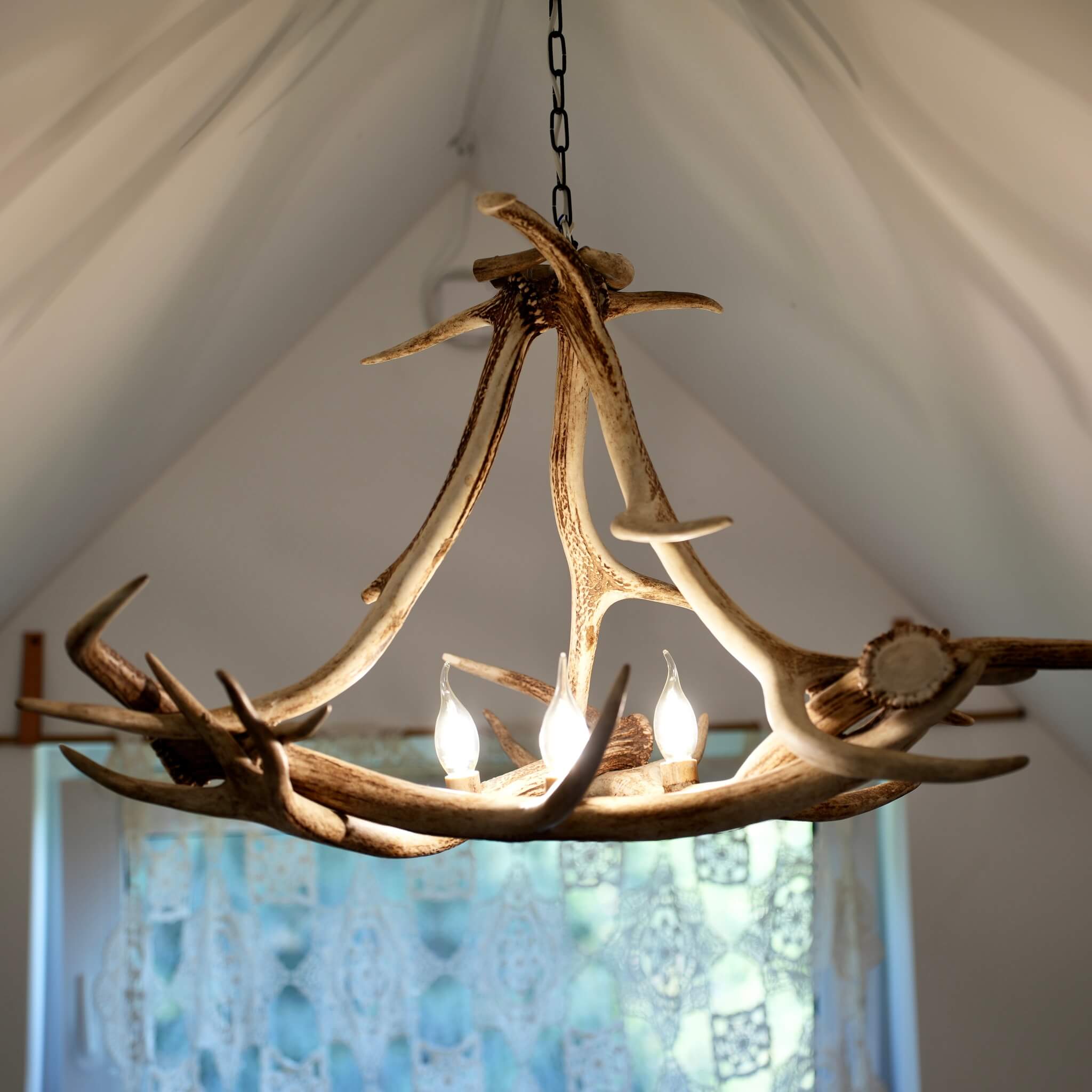 Modern antler chandelier hanging in bedroom.
