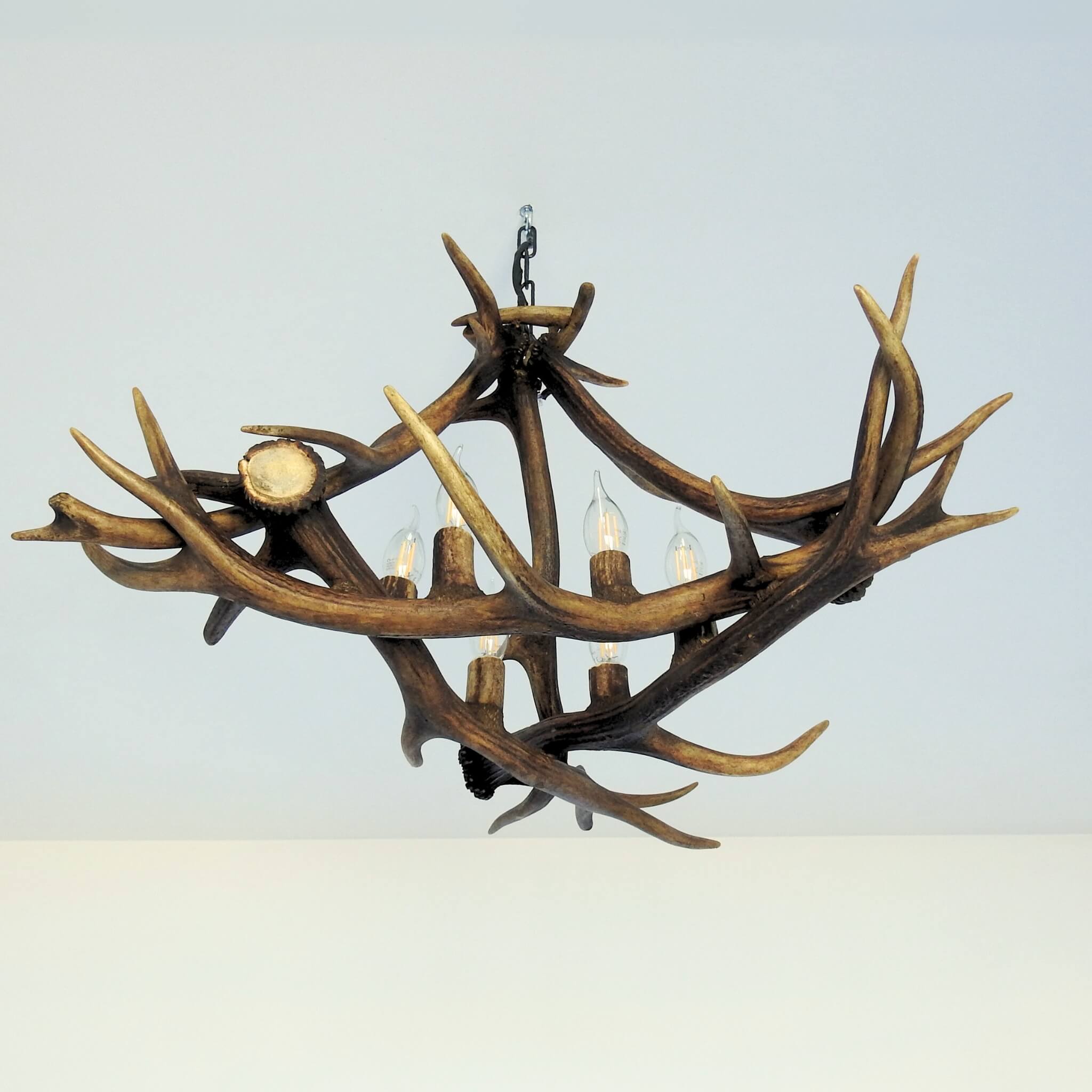 Triangle shape antler chandelier hanging on chain.