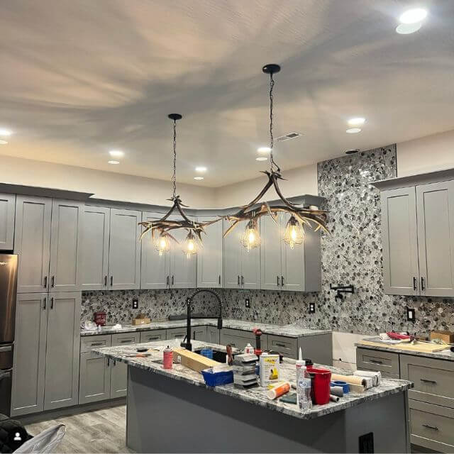 2 small antler pendant lamps hang over kitchen island in modern rustic home.