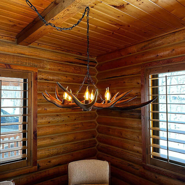 Real deer antler chandelier for 6 lights hanging on chain over the table.