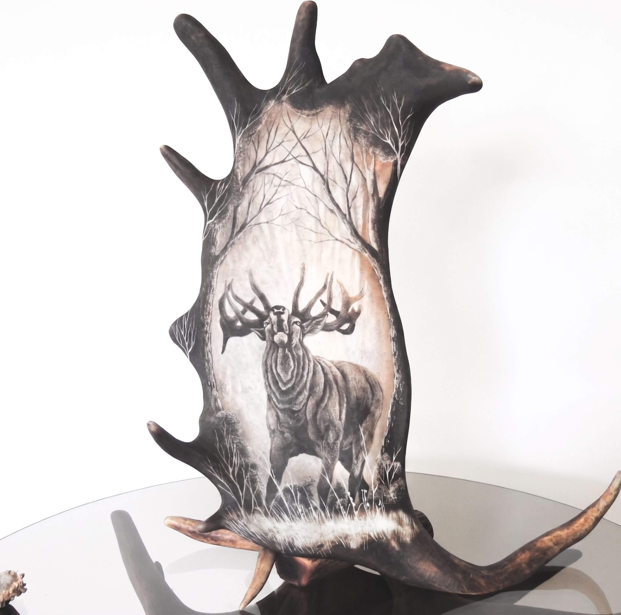 Decorative antler carving art with roaring red deer design on a white background.