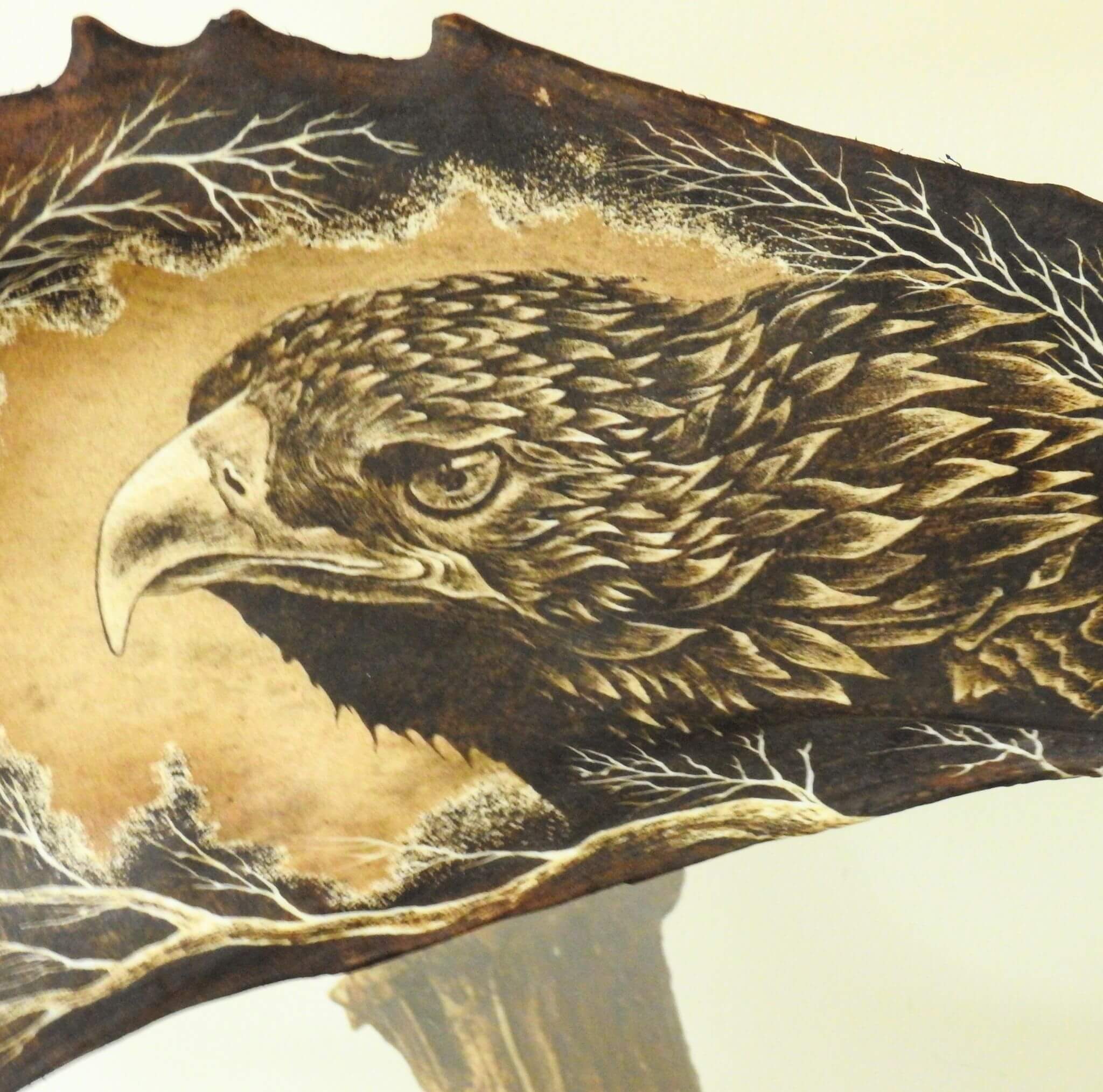 Carved in antler eagle head with detailed feathers on a branch.